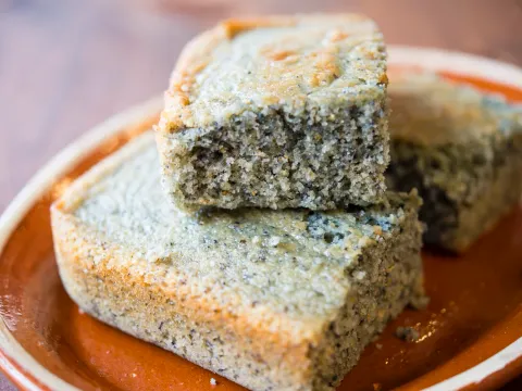 Two thick slices of Alta Baja Market's New Mexican blue corn cornbread stacked on a rustic terracotta plate
