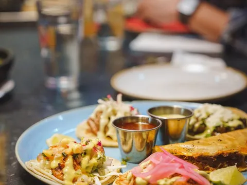 A plate of assorted street tacos with dipping salsas and lime at Tacos Tequila Whiskey