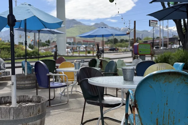 The patio at Lone Star Taqueria in Cottonwood Heights: colorful vintage metal chairs and umbrella-shaded tables with the Wasatch mountains in the background
