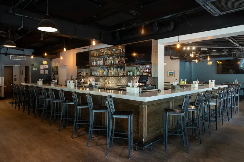 Interior bar and dining room at Cantina 76 on Main Street in Columbia, with a long marble-topped bar, bottle-lined back bar, and hanging Edison-style lights