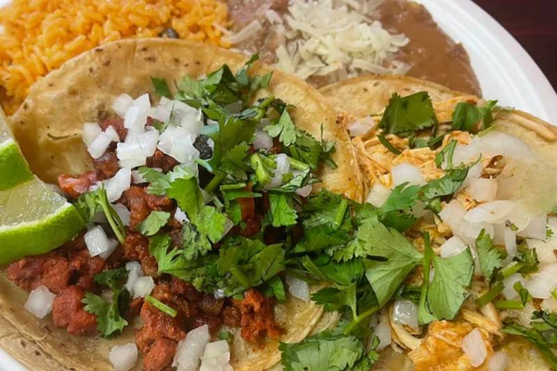 Plate of al pastor and chicken street tacos with Mexican rice and refried beans at Tacos Don Jose