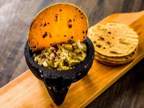 Smoked trout guacamole served in a stone molcajete with a toasted tortilla chip and stacked corn tortillas at Chavela's in Brooklyn