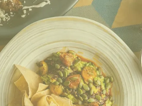 Overhead shot of a guacamole dish topped with pepitas at BelAir Cantina, served with tortilla chips and three salsas