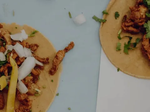 Two al pastor street tacos topped with cilantro, onion and lime at The Taco Stand in downtown San Diego