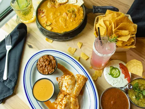 Spread of melting-pot cheese dip, tamales with chili and queso, tortilla chips, salsas and cocktails at Heights Taco & Tamale Co. in Little Rock, Arkansas